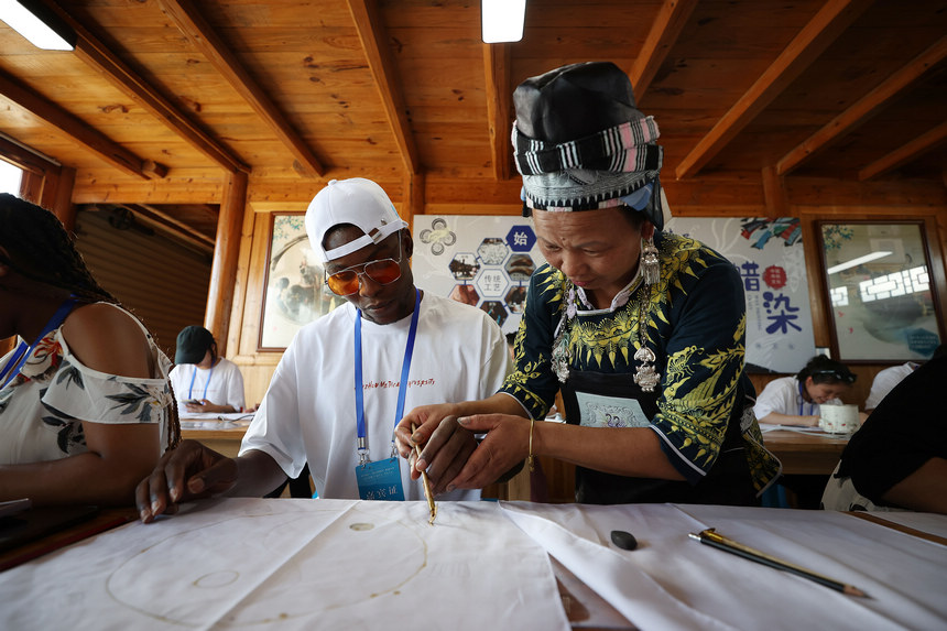 7月21日，手工藝人在指導留學生學習苗族蠟染繪畫。
