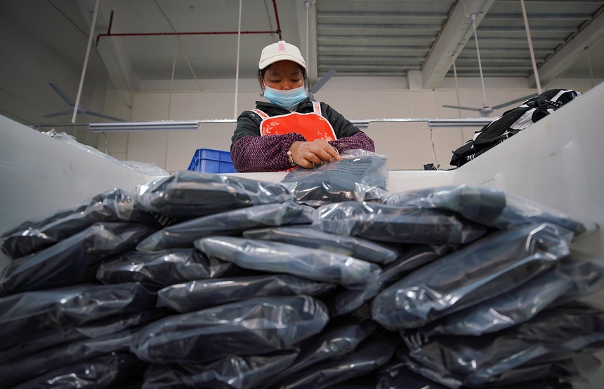 10月11日，工人在移民安置社區“幫扶車間”包裝加工好的背包。