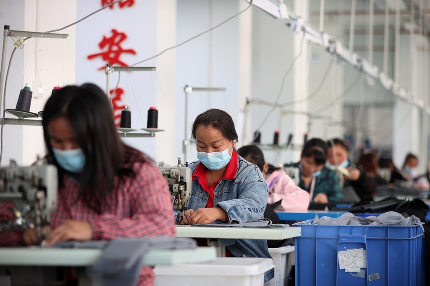 10月11日，工人在移民安置社區“幫扶車間”加工背包。 