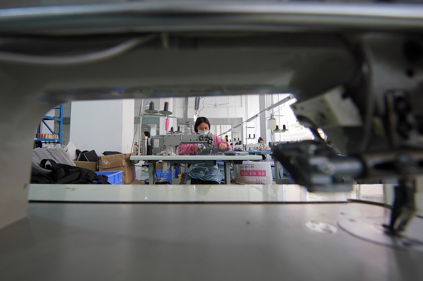 10月11日，工人在移民安置社區“幫扶車間”加工背包。