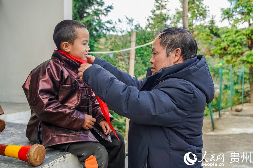 孟榮達老師正在為孩子系紅領巾。人民網 陽茜攝
