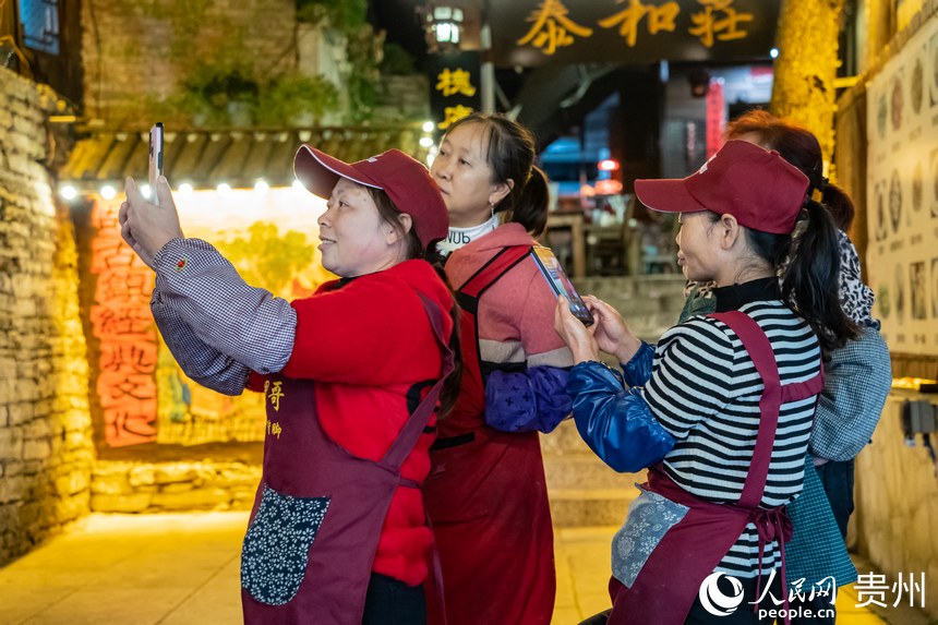 古鎮里的商販站在街道旁拍攝古鎮新貌。人民網 陽茜攝