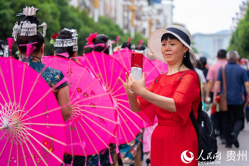 圍觀的群眾用手機拍攝少數民族同胞巡游。人民網記者 涂敏攝