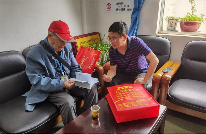 2 圖為興仁市委組織部副部長、市委老干局局長譚巍向退休干部覃登濤講解長護險政策。