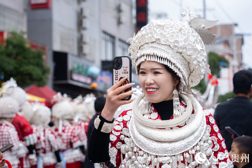 身著盛裝參加“蘆笙會”的苗族同胞為參加游演的同伴拍照。人民網記者 涂敏攝