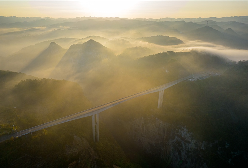 11月28日清晨，貴畢公路六廣河特大橋與云海、山川交相輝映，構成一幅壯美的交通畫卷。