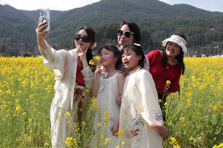 圖為游客們在油菜花田里拍照打卡。