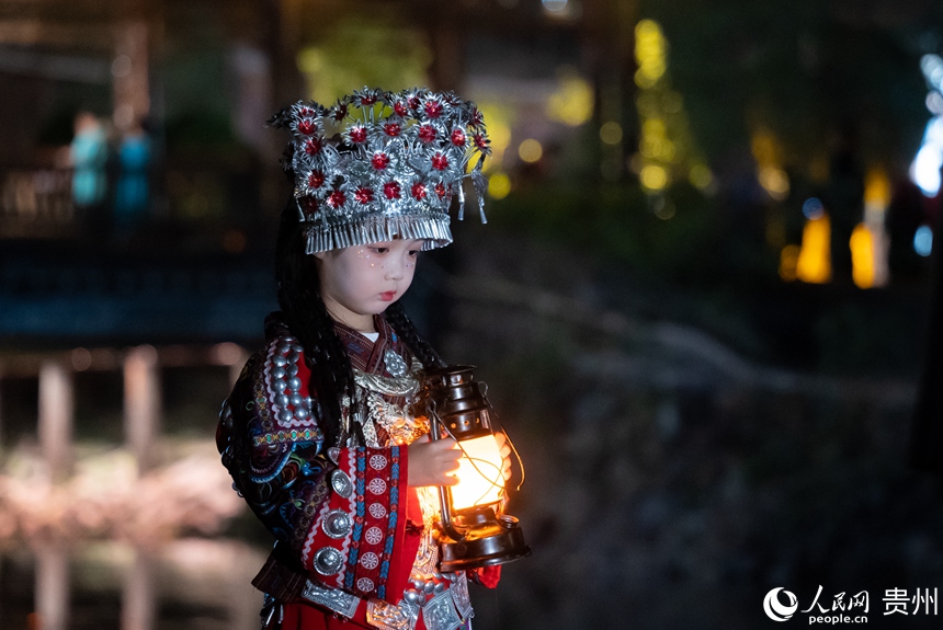 前來游玩的小朋友身著苗族特色服飾在景區內打卡拍照。人民網記者 涂敏 攝