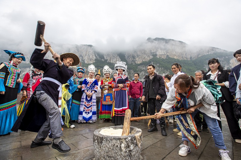 6月7日，貴州省畢節市黔西市新仁苗族鄉化屋村，村民們和游客打糍粑。