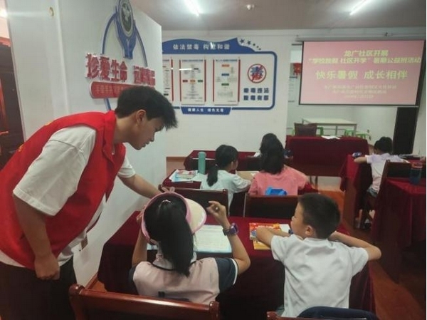 大學生志愿者正在輔導督促學生們做暑假作業。