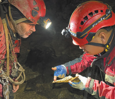 讓·波塔西（左）和中國專家在雙河洞一處支洞內觀察大熊貓化石。