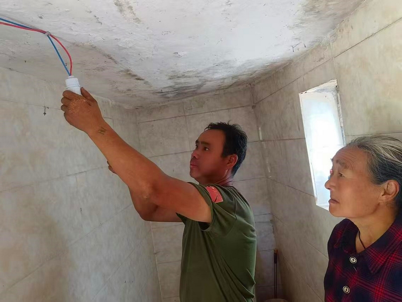 (2)李大明幫助付興文家接通電路。雷祥貴 攝