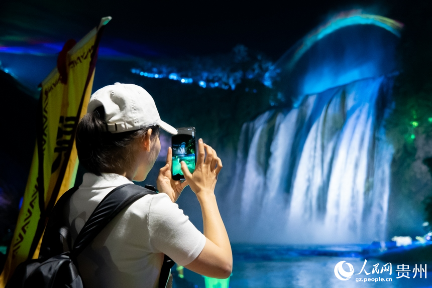 游客在夜間黃果樹瀑布前打卡拍照。人民網記者 涂敏攝