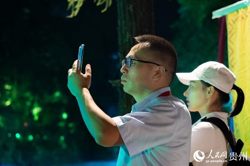 游客在夜間黃果樹瀑布前打卡拍照。人民網記者 涂敏攝