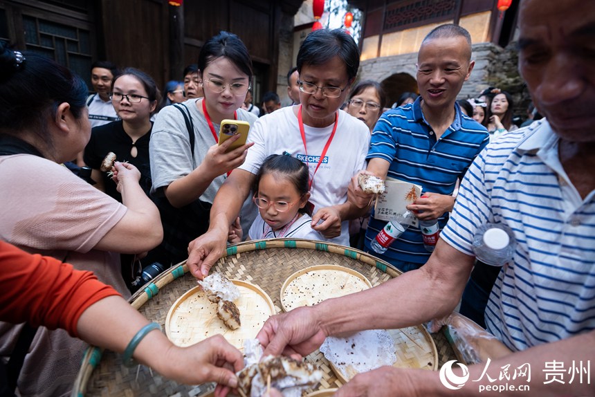 屯堡內，游客品嘗當地特色糍粑。人民網記者 涂敏攝