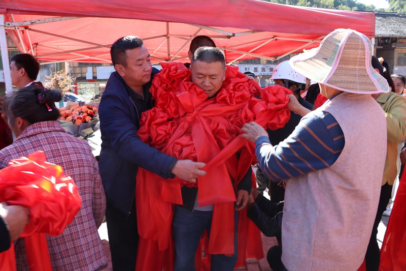 朱涌胸前戴滿了村民送的大紅花。圖片由獨山縣融媒體中心提供