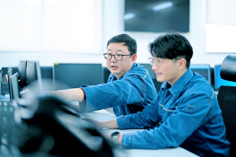 周敬余（左）給新員工講解監控信號的作用。陳濤攝