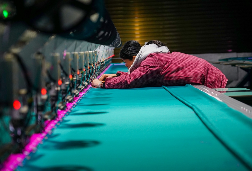 在貴州省從江縣美娥社區一家民族刺繡企業生產車間，工人在用數控機床生產刺繡產品。