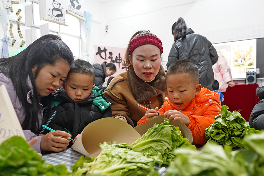 2025年3月6日，貴州省畢節市納雍縣龍場鎮中心幼兒園“溫情三八·感恩有您”活動現場，家長和孩子們一起做手工。 楊 英 攝