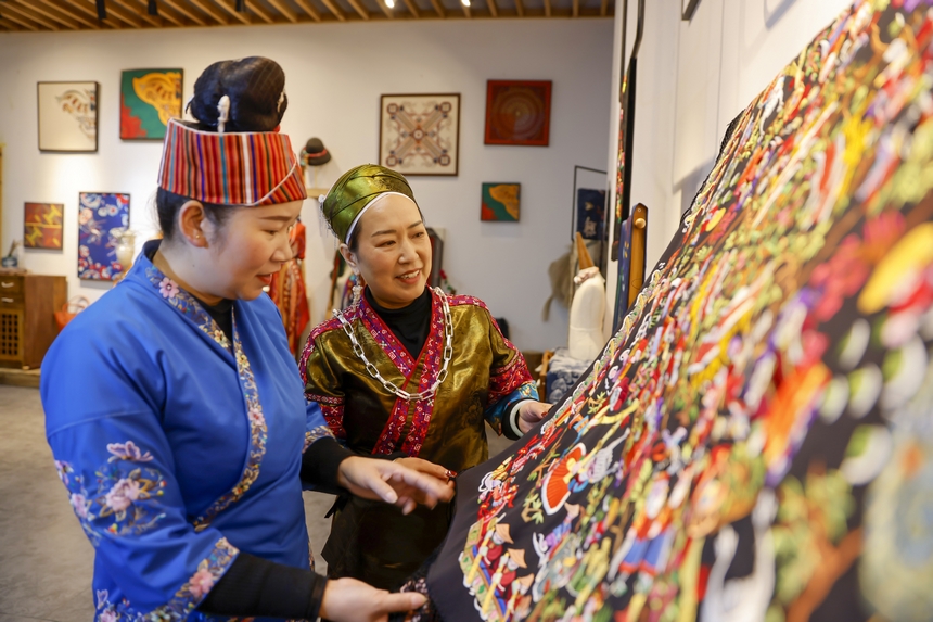 龍祿穎（右）與公司員工在交流苗繡技法。