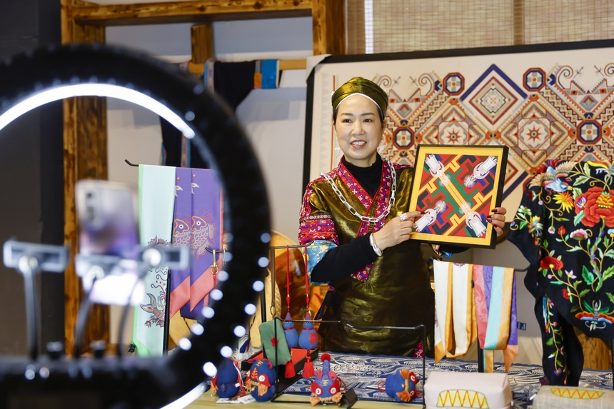 龍祿穎在公司的鄉村振興直播間推介苗繡文創產品。