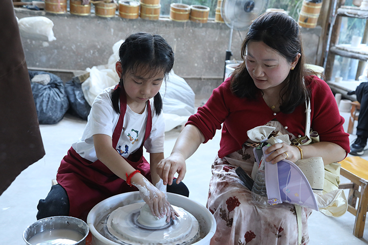 家長帶著孩子體驗當地瑤陶文化。