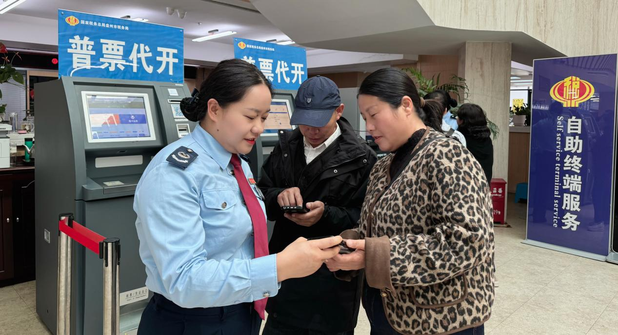 圖為 稅務干部輔導納稅人使用電子稅務局APP開具發票 張玉英/攝