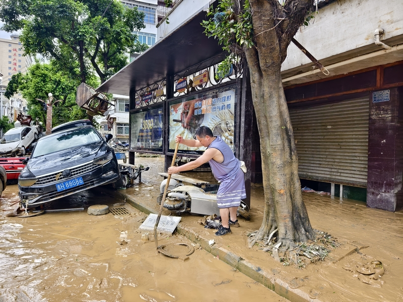 榕江縣稅務局黨委委員、副局長陳風在清掃縣城主大街淤泥。