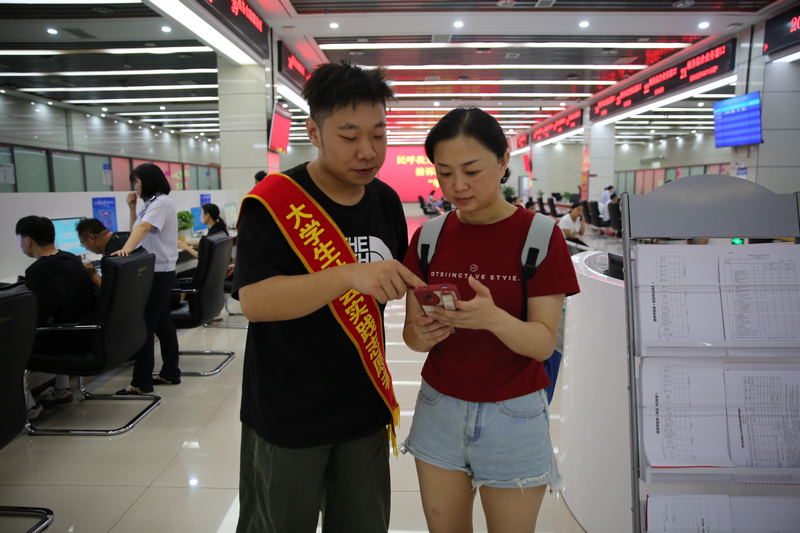 大學生志愿者輔導納稅人通過手機端電子稅務局開具發票。鄭婷攝