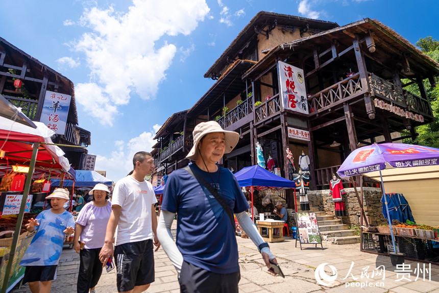 游客在景區內的海坪彝族特色旅游度假小鎮參觀游覽。人民網記者 涂敏攝