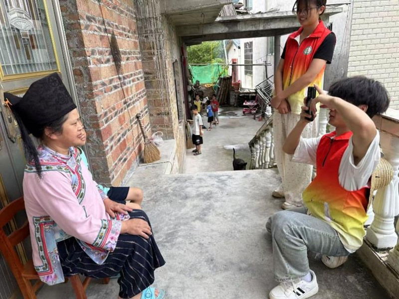 圖為志愿服務隊員調研完幫村民拍照。