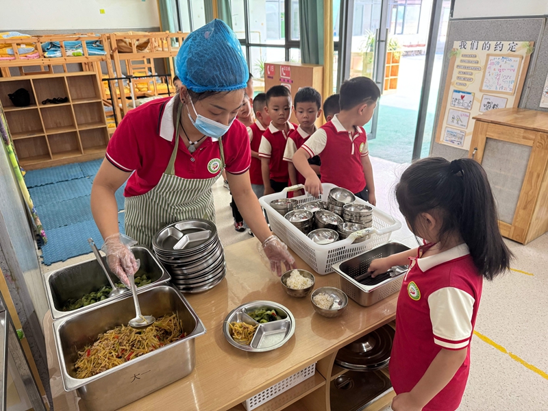 幼兒園工作人員為孩子們分餐，餐食豐富多樣。謝永恒  攝.jpg