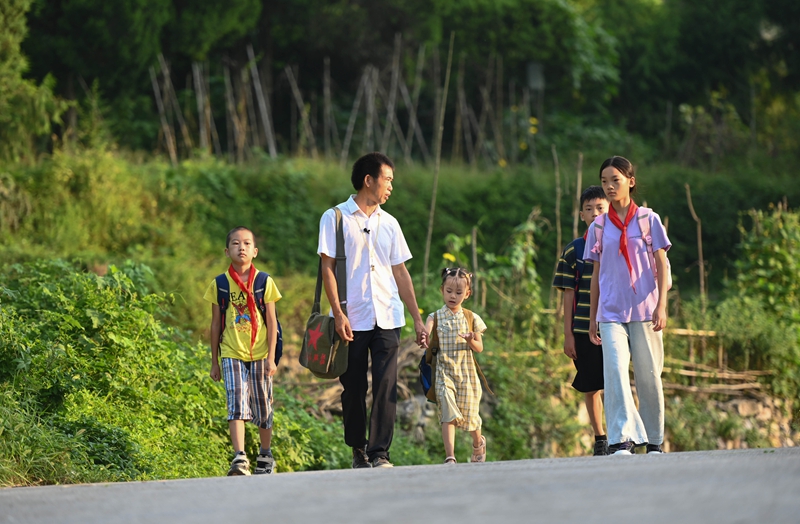 松桃苗族自治縣迓駕鎮教師任達兵帶著學生走在上學路上。謝慧芳攝 (2).JPG