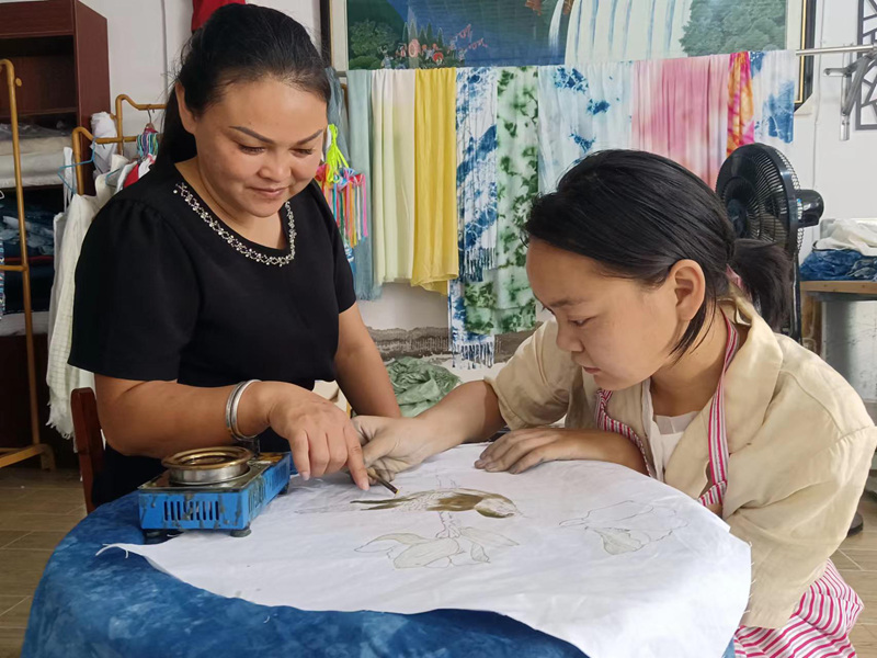 圖為梁海蘭指導梁玉芳畫蠟。
