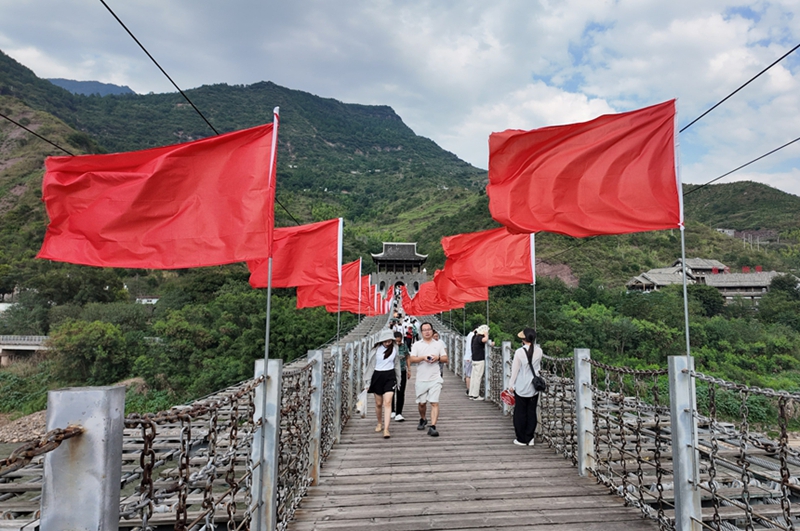 鐵索橋上一排排整齊懸掛的紅旗迎風招展。姚瑤 攝.jpg