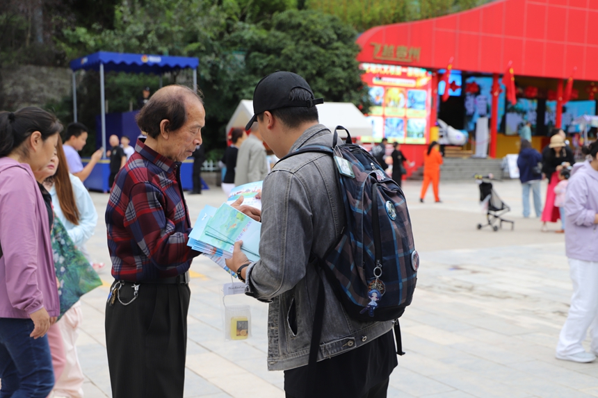 云巖區文體廣電旅游局工作人員正將《旅游安全實務手冊》遞到游客手中，準備進行詳細講解。