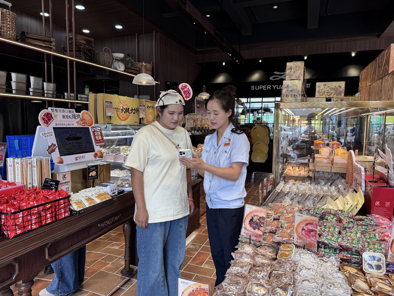 圖為 稅務干部指導納稅人使用電子稅務局APP開具發票。李娜莎攝