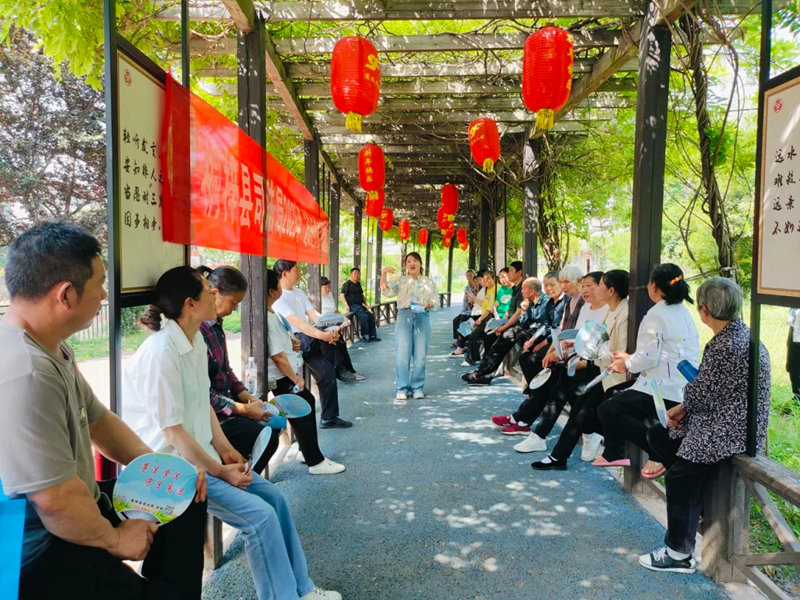 在松坎鎮新時代文明實踐廣場法治文化長廊，縣司法局“專業說法”宣講隊成員謝紅霞正在為該鎮茅壩社區居民開展普法宣傳。