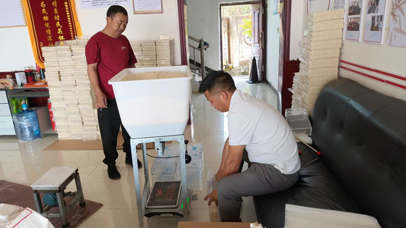 工作人員幫助村民真空包裝大米。