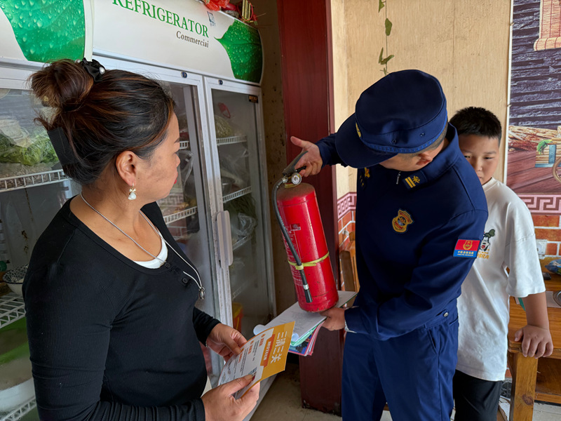 消防員仔細檢查商鋪內滅火器是否完好無損。