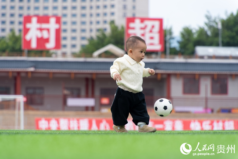 “村超”球場上，11個月大的孩子跟著足球撲騰。人民網記者 涂敏攝